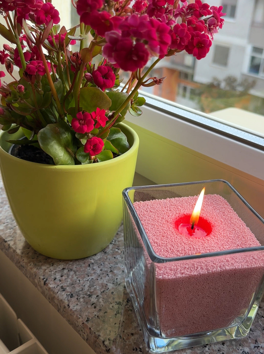 Staklena četvetasta posuda i peščana sveća .